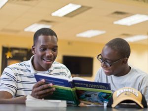 Two students looking at a book and engaging with each other