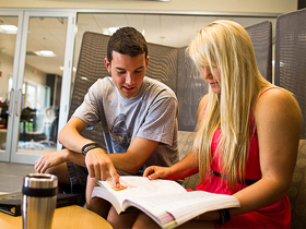 A male student pointing to a page in a book
